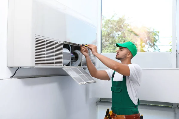 Professionele technicus die de moderne airconditioner binnenshuis onderhoudt — Stockfoto