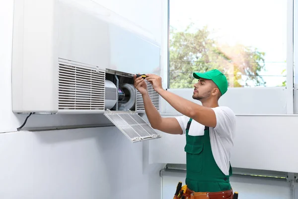 Professional technician maintaining modern air conditioner indoors — Stock Photo, Image