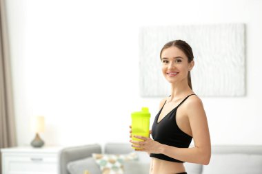 Evde protein içeceği olan atletik genç bir kadın.