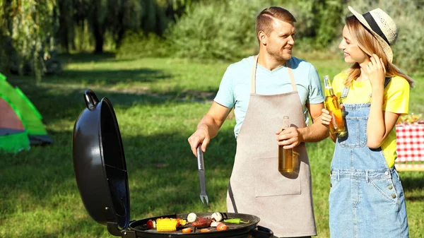 Coppia felice cucinare cibo sul barbecue nel parco — Foto Stock