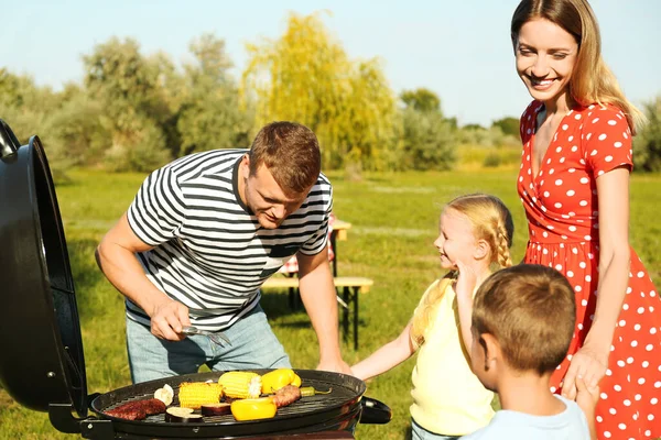 Familie fericită cu copii mici care au grătar în parc — Fotografie, imagine de stoc