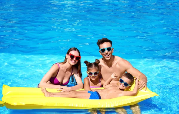 Famille heureuse avec matelas gonflable dans la piscine — Photo