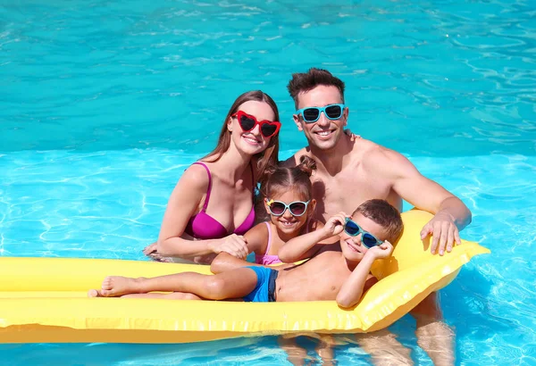 Счастливая семья с надувным матрасом в бассейне — стоковое фото
