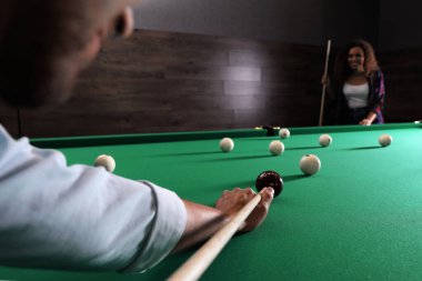 Bilardo oynayan genç bir adam ve arka planda bulanık bir Afro-Amerikan kadın, yakın plan. Metin için boşluk