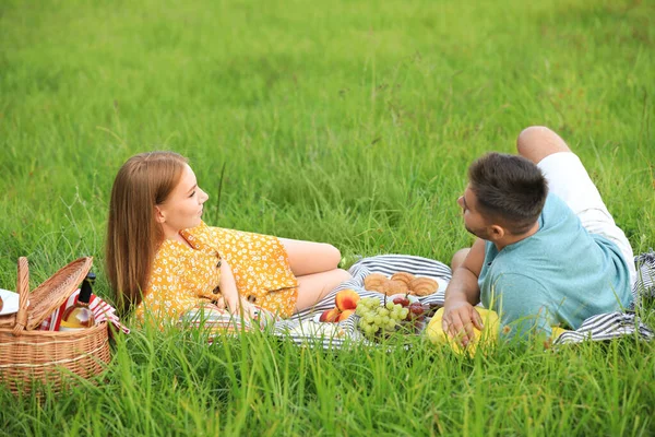 快乐的年轻夫妇在公园的绿草上野餐 — 图库照片