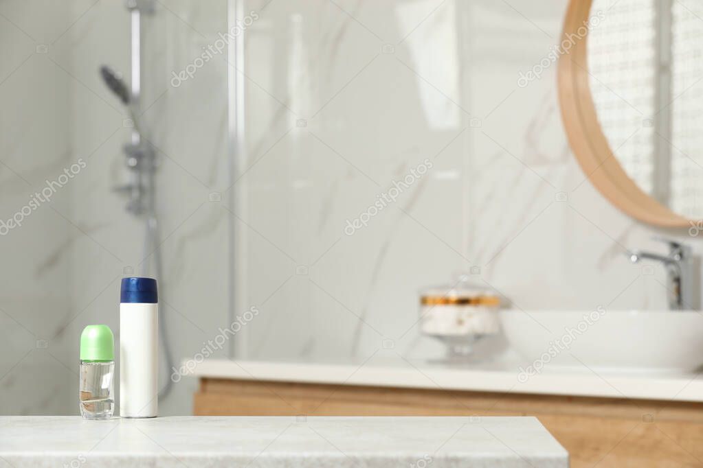 Different deodorants on table in bathroom, space for text