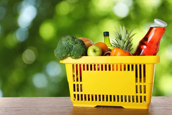 Panier avec produits d'épicerie sur table en bois sur fond flou — Photo