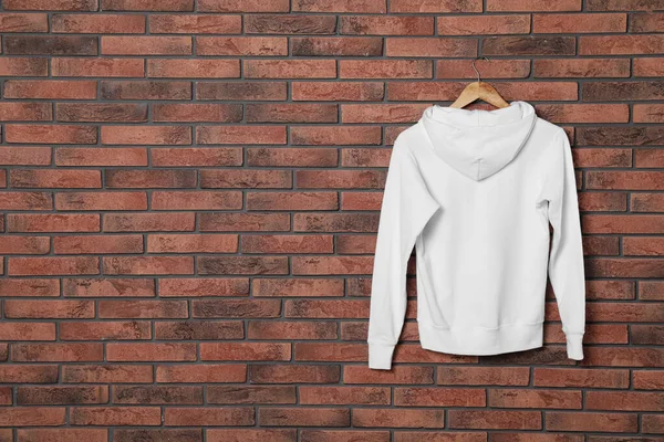 Hanger met nieuwe trui aan bakstenen muur, model voor ontwerp — Stockfoto