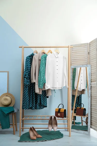 Porte-armoire avec des vêtements et des chaussures pour femmes au mur de couleur dans la chambre — Photo