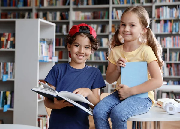 Niño y niña leyendo libro en la biblioteca — Foto de Stock