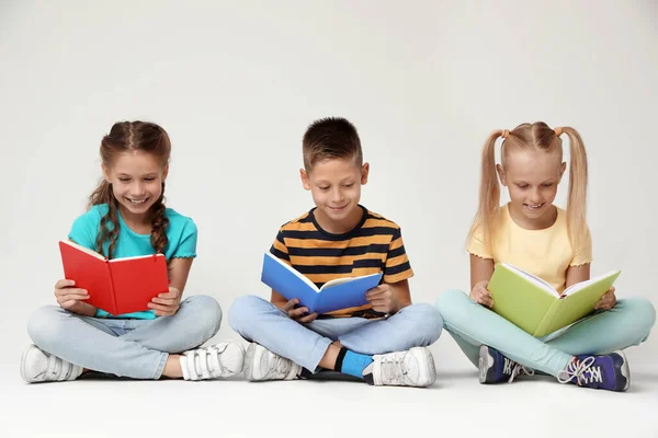 Petits enfants lisant des livres sur fond gris — Photo