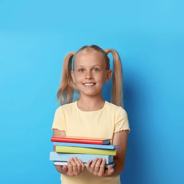 Porträtt av söt liten flicka med böcker på blå bakgrund. Läsbegrepp — Stockfoto