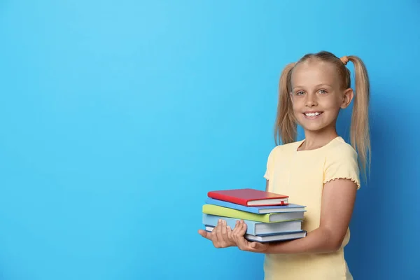 Portrét roztomilé holčičky s knihami na modrém pozadí, prostor pro text. Koncept čtení — Stock fotografie