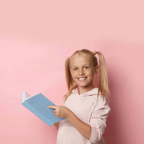 Retrato de linda niña leyendo libro sobre fondo rosa — Foto de Stock