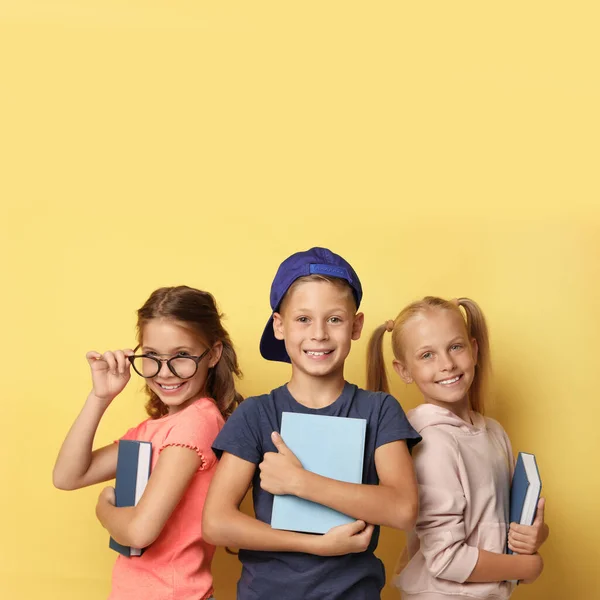 Niños pequeños con libros sobre fondo amarillo. Concepto de lectura —  Fotos de Stock