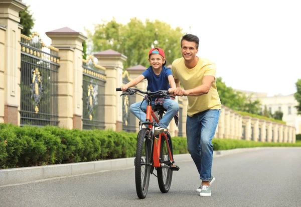 Papá enseñando a su hijo a montar en bicicleta al aire libre — Foto de Stock