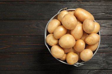 Siyah ahşap arka planda çiğ organik patates, üst manzara. Metin için boşluk