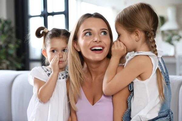 Cute little girls telling secrets to their mother in living room — Stock Photo, Image