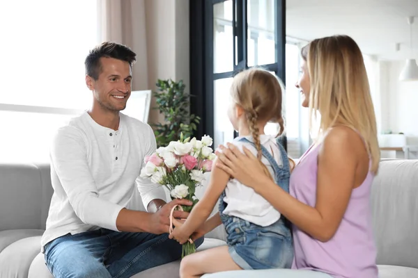 Młody mężczyzna gratuluje żonie i córce w salonie — Zdjęcie stockowe