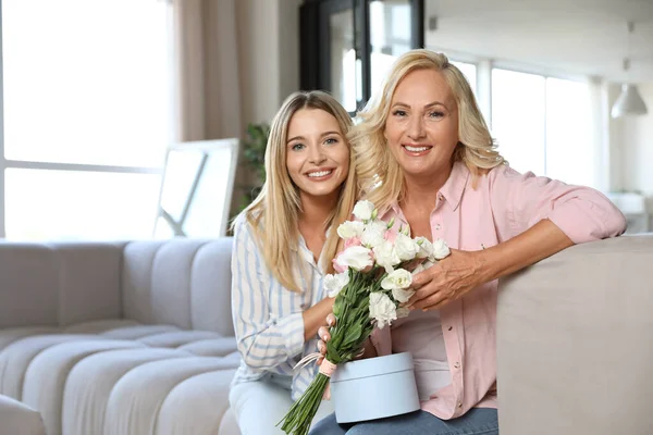 Young woman congratulating her mother in living room — Stock Photo, Image