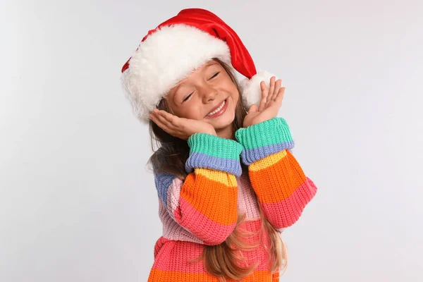 Happy little child in Santa hat on light grey background. Christmas celebration — Stock Photo, Image