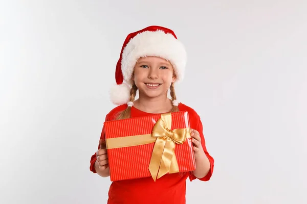 Criança feliz em chapéu de Papai Noel com caixa de presente em fundo cinza claro. Celebração de Natal — Fotografia de Stock