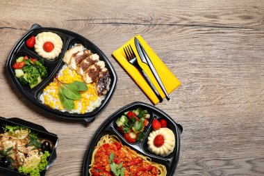 Ahşap masa üzerinde farklı yemekler ile Öğle yemeği kutuları, düz yatıyordu. Sağlıklı gıda dağıtımı