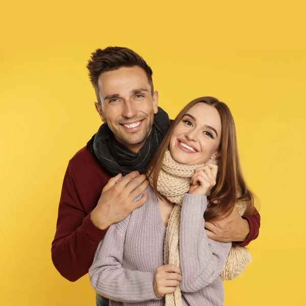 Feliz pareja joven en ropa de abrigo sobre fondo amarillo. Temporada de invierno — Foto de Stock