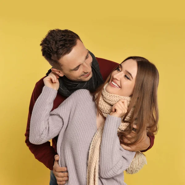 Feliz pareja joven en ropa de abrigo sobre fondo amarillo. Temporada de invierno — Foto de Stock