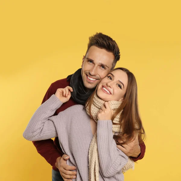 Feliz pareja joven en ropa de abrigo sobre fondo amarillo. Temporada de invierno — Foto de Stock