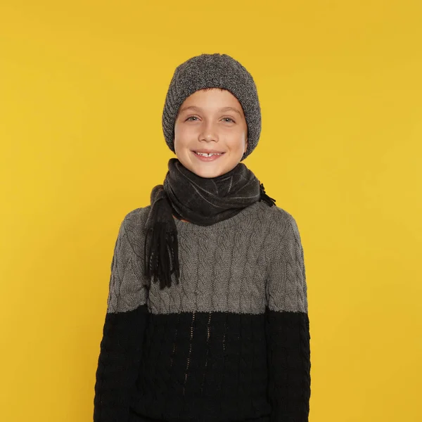 Menino bonito em roupas quentes no fundo amarelo. Temporada de Inverno — Fotografia de Stock