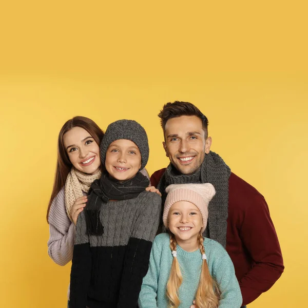 Família feliz em roupas quentes no fundo amarelo. Temporada de Inverno — Fotografia de Stock