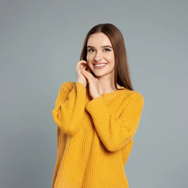 Hermosa mujer joven en suéter amarillo sobre fondo gris. Temporada de invierno —  Fotos de Stock