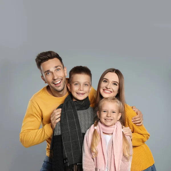 Familia feliz en ropa de abrigo sobre fondo gris. Temporada de invierno — Foto de Stock