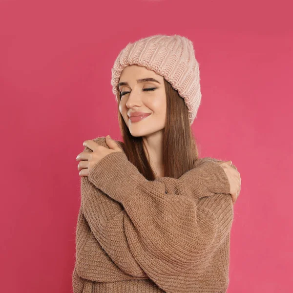 ピンクの背景に帽子とセーターの美しい若い女性。冬の季節 — ストック写真