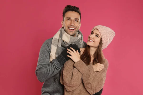 Ευτυχισμένο νεαρό ζευγάρι με ζεστά ρούχα σε ροζ φόντο. Χειμερινή περίοδος — Φωτογραφία Αρχείου
