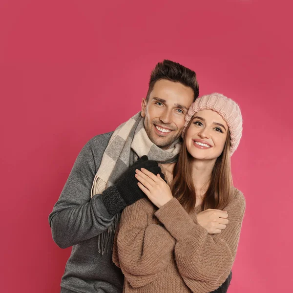 Feliz pareja joven en ropa de abrigo sobre fondo rosa. Temporada de invierno — Foto de Stock