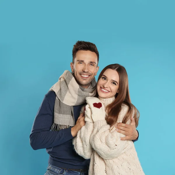 Feliz pareja joven en ropa de abrigo sobre fondo azul. Temporada de invierno —  Fotos de Stock