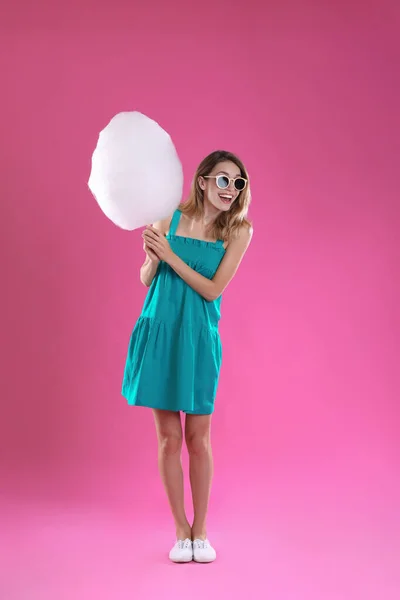 Mujer joven feliz con algodón de azúcar sobre fondo rosa — Foto de Stock