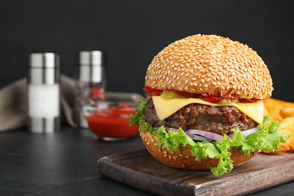 Pyszny burger z kotletem mięsnym na czarnym stole. Miejsce na tekst — Zdjęcie stockowe