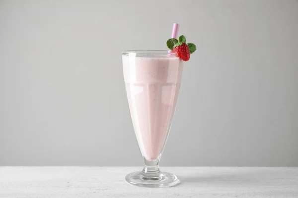 Tasty strawberry milk shake in glass on white wooden table — Stock Photo, Image