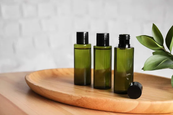 Mini botellas con productos cosméticos sobre mesa de madera sobre fondo blanco. Espacio para texto — Foto de Stock