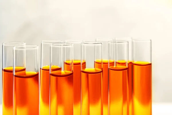 Närbild av många provrör med orange vätska på färg bakgrund — Stockfoto