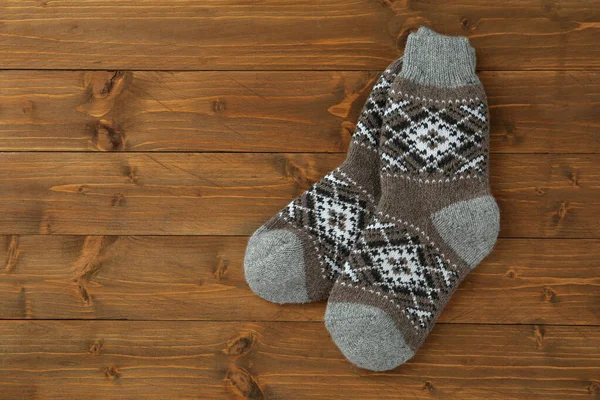 Knitted socks on wooden background, flat lay with space for text — Stock Photo, Image