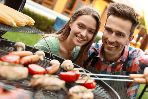 Ung mand og kvinde nær grill grill udendørs - Stock-foto