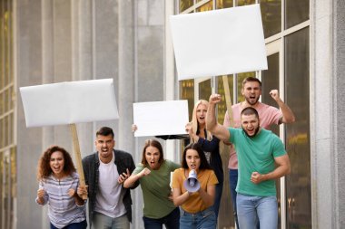 Dışarıda megafonla protesto yapan öfkeli genç bir kadın.