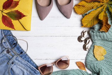 Beyaz ahşap zemin üzerinde kalın giysiler ve sonbahar yaprakları ile düz kompozisyon, metin için boşluk