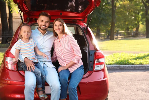 Happy family sitting in car 's trunk outdoors — стоковое фото