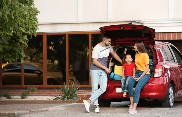 Glad familj nära bil med öppen baklucka på gatan — Stockfoto