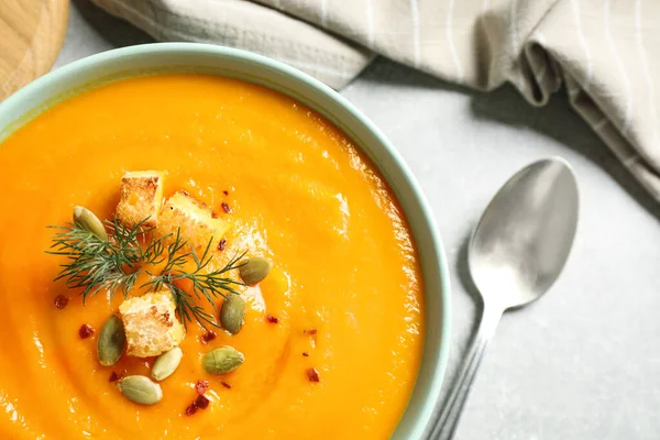 Delicious pumpkin soup in bowl on grey table, top view — Stock Photo, Image